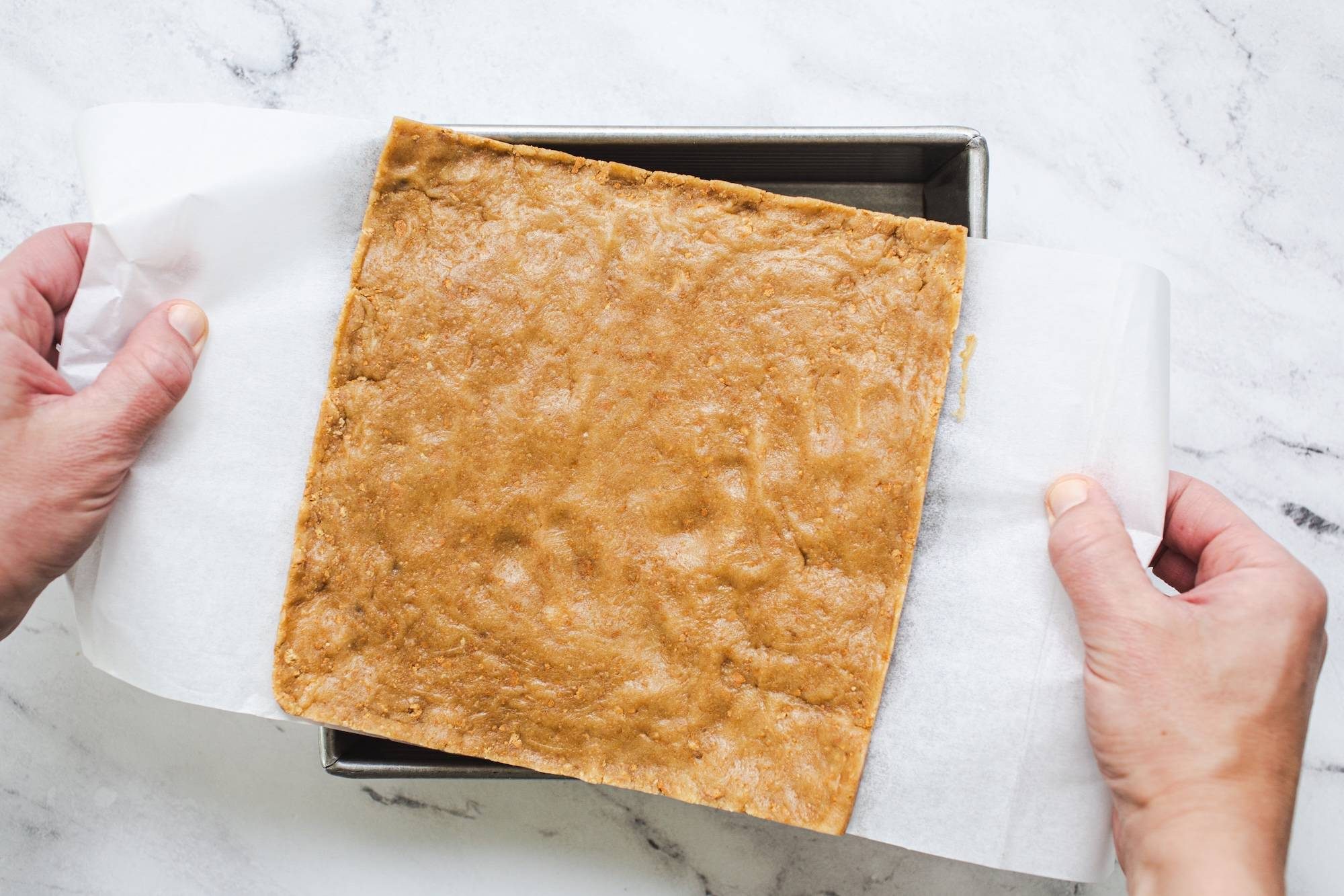 Lifting top layer of dough in a pan.