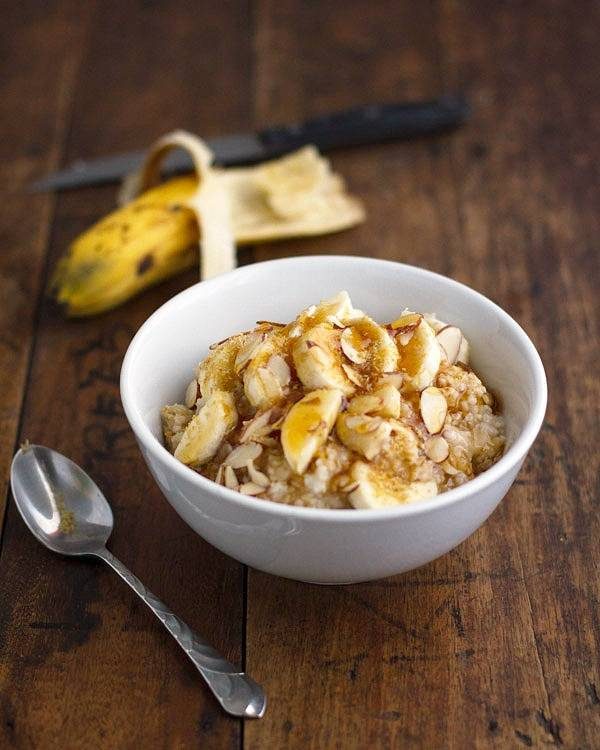Steel cut oats with bananas in a white bowl with a spoon.