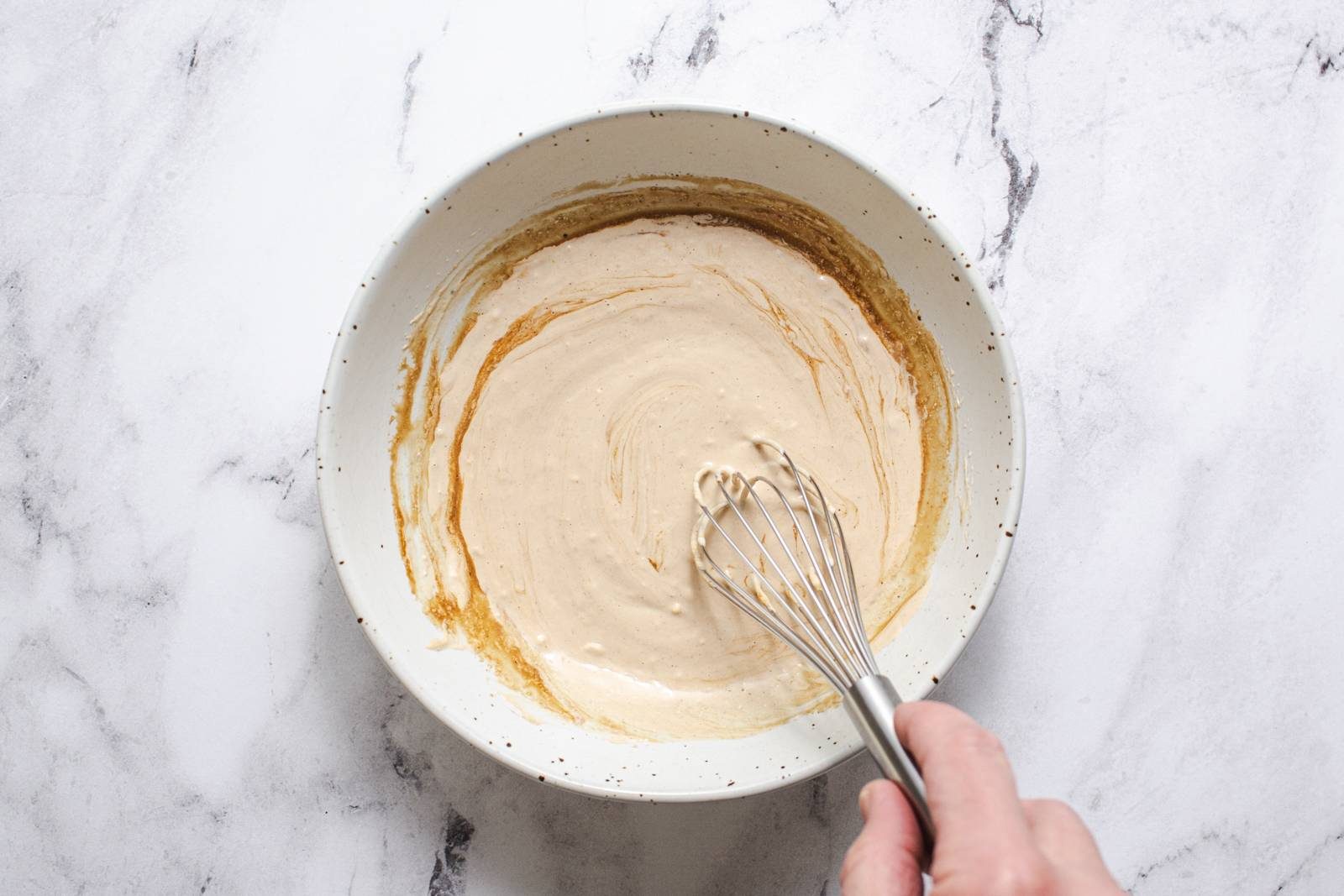 Whisking caesar dressing in a bowl.
