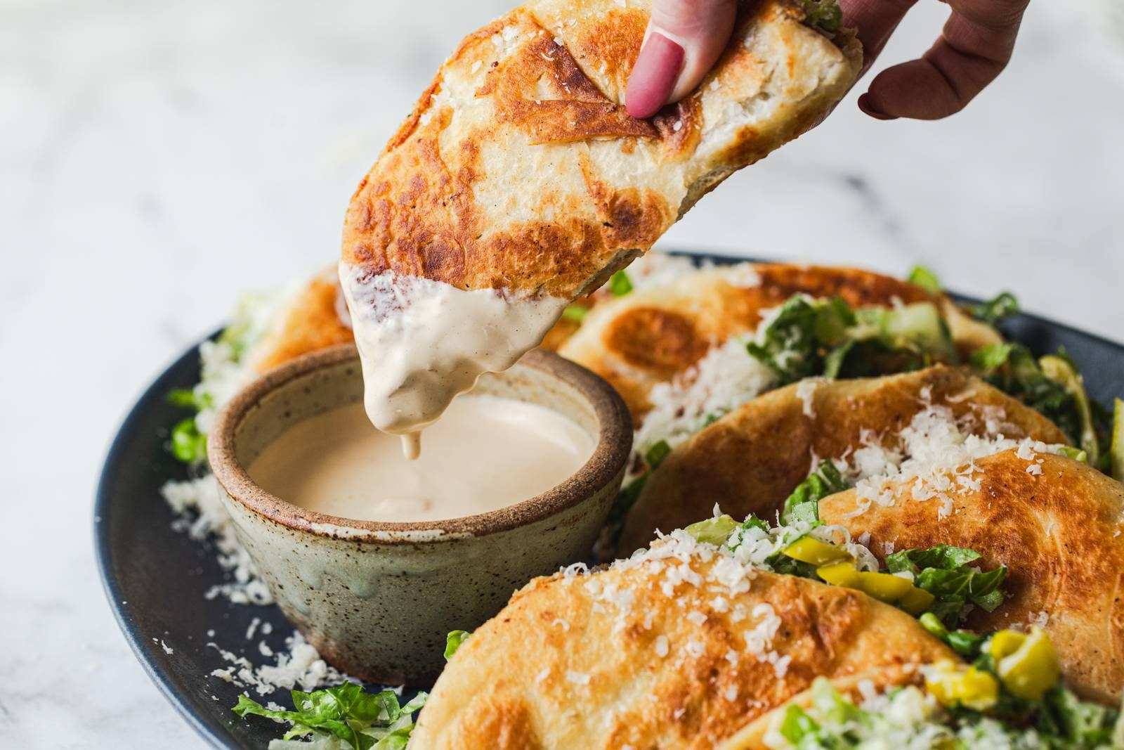 Dipping smash tacos into caesar dressing.