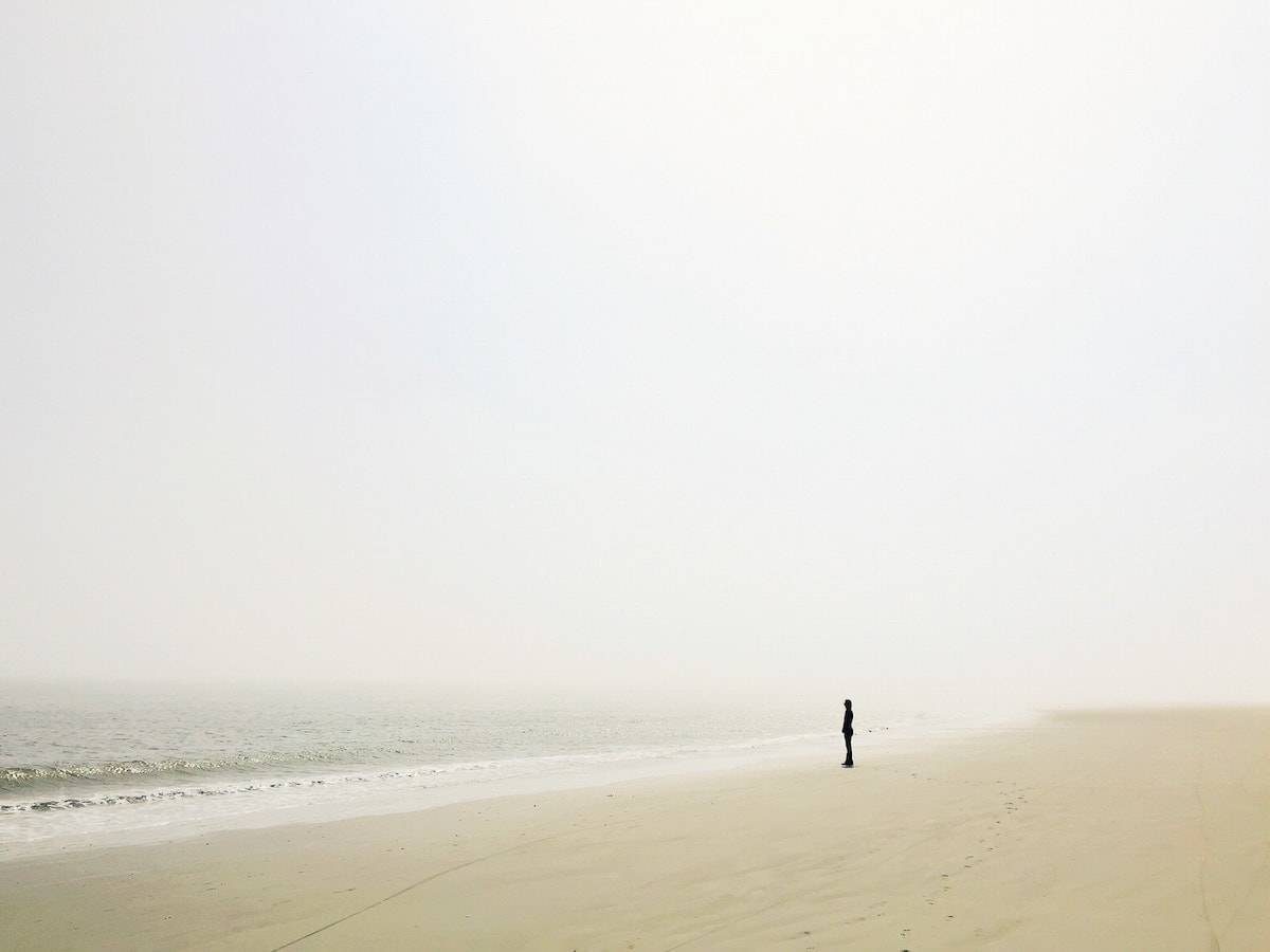 Tiny person standing on the ocean shore.