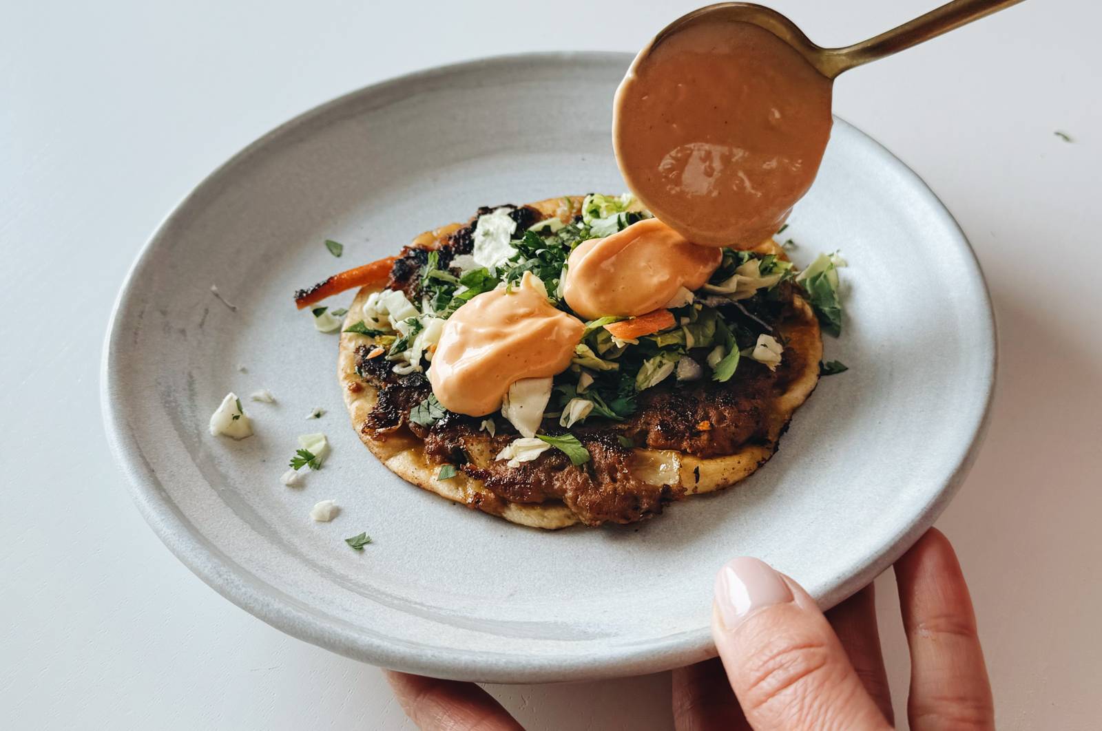 Spooning gochujang sauce on egg roll tacos.