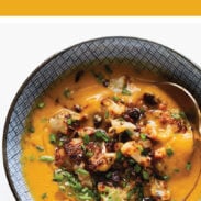 Sweet Potato Soup in a bowl with cauliflower crumbled on top.