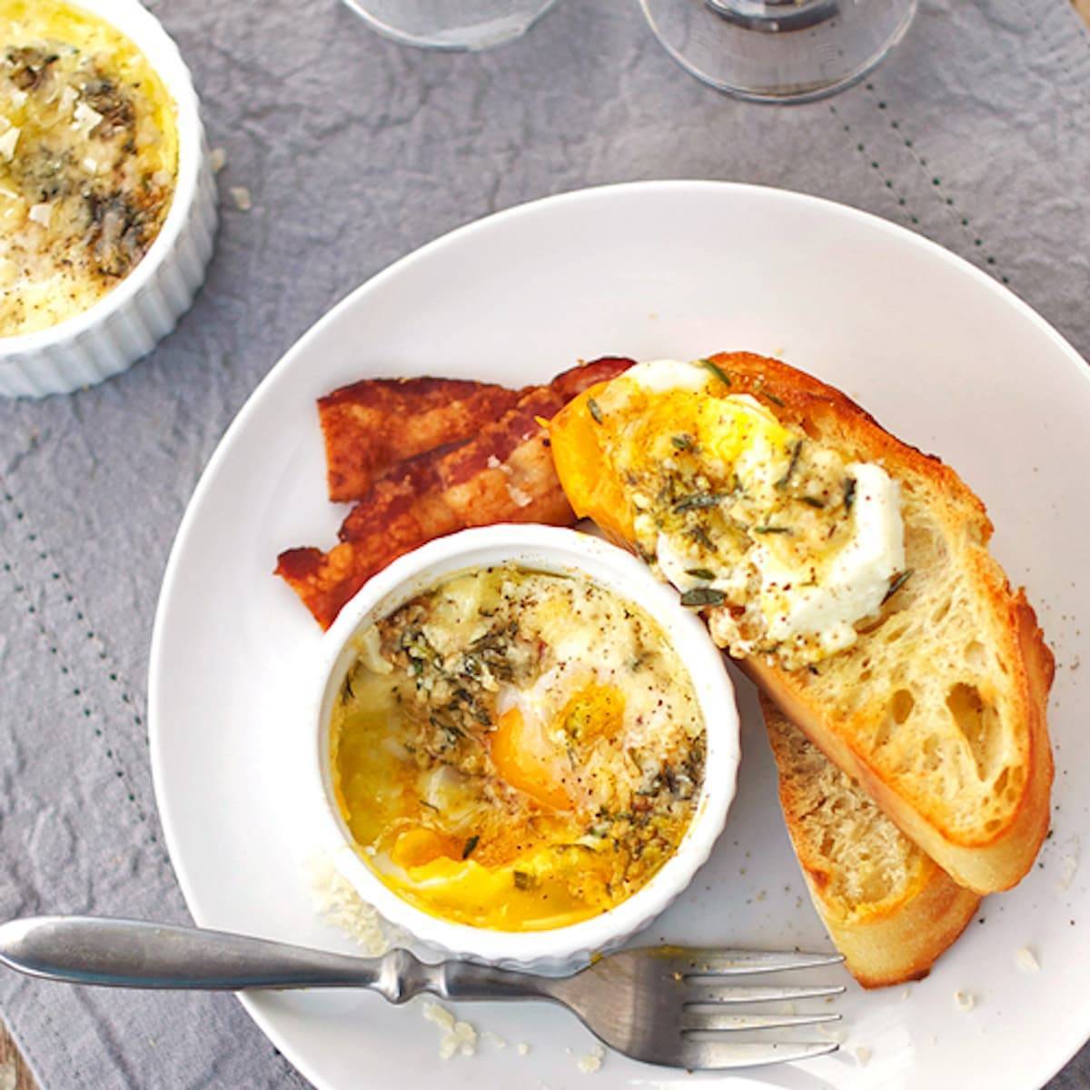 Parmesan baked eggs in a dish and on pieces of bread on a plate.